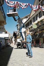 Bereit für das Freilichtspektakel: Tourismusdirektor Frédéric Füssenich schaut zu, wie Martin Amstutz vom Werkhof die erste Girlande in der Dorfstrasse montiert. (Bild: Philipp Unterschütz (Engelberg, 5. Juli 2017))