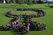 Die Schule Giswil hat in diesem Jahr das Motto "Wurzlä schlah, wachsä lah". Im Bild: Die Schülerinnen und Schüler sowie die die Co-Schulleiter Isabelle Wyss und Thomas Heiniger stellten sich symbolisch zu einem grossen Baum auf. (Bild: Neue OZ/Birgit Scheidegger)