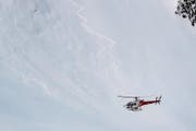 Ein Helikopter fliegt über den Ort, an dem die Lawine niedergegangen ist. (Bild: Valentin Flauraud / Keystone (Finhaut, 18. Februar 2018))
