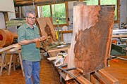 Der Lungerer Bildhauer Karl Imfeld hält ein Modell seiner Bartheke in den Händen. Daneben entsteht das Kunstwerk aus dem Holz eines 200-jährigen Riesen-Mammutbaums. (Bild Robert Hess)