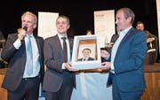 Bundesrat Ignazio Cassis (Mitte) erhält von Urs Frei, Präsident der FDP Toggenburg, einen Schlorzifladen mit Porträt und ein Panorama-Messer mit der Silhouette der Churfirsten. Links im Bild Moderator Sven Bradke. (Bild: Ralph Ribi)