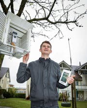 Florian Zangl im Garten vor seiner elterlichen Wohnung. Die Daten des Thermometers im Wetterhüttchen und vom Windmesser auf der Schaukel werden per Funk an die Wetterstation übermittelt. (Bild: Ralph Ribi)