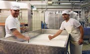 Käsermeister Johannes Eberle (links) und Migrant Hayatullah Mohammadi beim Vorreifen der Milch. (Bild: Yvonne Aldrovandi-Schläpfer)