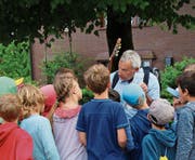Die Kinder hängen an den Lippen von Rolf Zingg, der sie in St. Georgen durch den Wald führt. (Bild: Bettina Sieber)