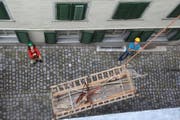 Christelle Wick und Hansruedi Kugler sorgen dafür, dass Fahrgestell und Aufbau des Lediwagens beim Transport in den Estrich des Bezirksgebäudes die Hauswände nicht beschädigen. (Bild: Martin Knoepfel)