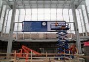 Arbeiter montieren über den Treppen der Rathausunterführung den neuen Bildschirm mit den Zugabfahrten. (Bild: David Gadze)