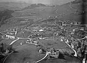 Das Riethüsli auf einer Luftaufnahme von Walter Mittelholzer vom 14. Mai 1924. Dort, wo heute in der Bildmitte Schulhaus, Kirche und neuere Wohnhäuser stehen, und auch auf Oberhofstetten wird das Gebiet durch die grosse Gärtnerei Wartmann geprägt. Vorne ist der «Scheffelstein» (mit Terrasse und Turm) und der Nestweier, gegenüber am rechten Bildrand der «Klotz» der Textilfabrik zu erkennen. An der Strasse, die links am «Scheffelstein» vorbeiführt, liegt das Restaurant Nest, dort, wo die Strasse ins Riethüsli abbiegt. (Bild: ETH-Bibliothek Zürich)