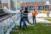Not macht erfinderisch: Flüchtlinge haben eine Abfallplache kurzerhand zu einer "Schneewanne" umfunktioniert, um damit den Hauptplatz des Paul-Grüninger-Stadion von Schnee zu räumen. (Bild: Urs Bucher)