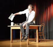 Stefan Waghubinger auf der Bühne in der Alten Turnhalle, in der Hand die Steuererklärung. (Bild: Nina Rudnicki)