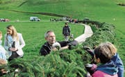Mosligerinnen und Mosliger binden den Weltrekord-Adventskranz auf der Wiese an der Hauptstrasse zwischen Mosnang und Libingen. (Bild: Michael Hug)
