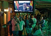 Enttäuschte Blicke in einer Bar während der Rede von Simbabwes Präsident Robert Mugabe. (Bild:)