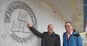 Stadtrat Daniel Meili und Sicherheitsverbund-Geschäftsführer Andreas Dobler vor dem Emblem auf der Hinterseite des Gebäudes.