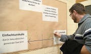 Nach der Gemeindeversammlung: Dieser Stimmbürger setzt seinen grünen Klebepunkt auf der Seite der Zweifach-Turnhalle. (Bild: Mathias Frei)