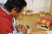 Rovei Eak rollt die Holzstäbchen für den «Besmer-Brenner» in die Jutematte. (Bild: Kurt Peter)