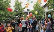 Janine Klingenstein, Leiterin der Tagesschule, und Projektleiter Ueli Wolf lassen inmitten von Kindern bunte Luftballons steigen. (Bild: Manuel Nagel)