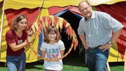 Animatorin Sabine Geiger und Schulleiter Jean-Philippe Gerber erklären Anina eine Nummer mit dem Feuerreifen. (Bild: Werner Lenzin)