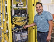 Werksmitarbeiter Manuel Herzog zeigt einen Knotenpunkt des Eschliker Glasfasernetzes in der Trafostation Riet. (Bild: PD)