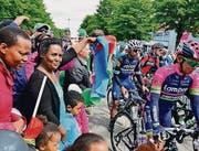 Grosser Bahnhof für die Rad-Cracks gestern beim Start zur Königsetappe: Maskottchen «Tourli» klatscht Kinderhände ab, viel Gedränge bei der Vorstellung der Teams beim Village auf dem Jumbo-Parkplatz; Zuschauer schicken die Fahrer los, Fabian Cancellara bei seiner letzten Tour. (Bilder: Max Eichenberger)