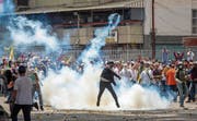 Ein Demonstrant wirft eine Tränengaspatrone zurück an den Absender. (Bild: Miguel Gutierrez/EPA (Caracas, 19. April 2017))