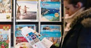 Die Kundin eines Reisebüros studiert einen Ferienkatalog. Noch ist den Schweizern die Reiselust nicht vergangen. (Bild: Michel Canonica)