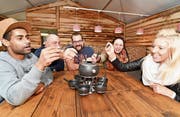 Sebastian Marx (Küche), Urs Schmidhauser (Betreiber), Markus Meile (Küche), Carla Alder und Marena Karner (beide Service) sitzen am sechs Meter langen Tisch Probe für das Fondue. (Bild: Manuel Nagel)
