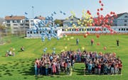 Die Schüler lassen Ballons steigen. Im Hintergrund sieht man die Container, wo der Unterricht während des Baus stattfindet. (Bild: Donato Caspari)