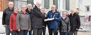 Walter Bosshard (blaue Jacke) übergibt Gemeindepräsident Reto Altherr die Petition zum Erhalt des Bahnschalters. (Bild: Mea Mc Ghee)