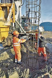 Die Bauarbeiter versenken ein rund 20 Meter langes Armierungsgitter ins mit Beton gefüllte Bohrloch. Polier Beat Meili kontrolliert mit der Wasserwaage die Neigung des Eisens. (Bild: Mario Testa)
