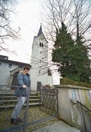 Daniela Müller, Vizepräsidentin der Kirchgemeinde, vor der Kirche. Rechts zwei der alten Bäume, die gefällt werden müssen. (Bild: Mario Testa)