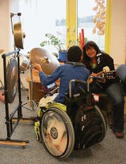 Der 19jährige A. K. freut sich über die Klänge, die er mit dem Becken und dem Gong erzeugen kann. Musiktherapeutin Dodo Trieblnig begleitet ihn mit der Gitarre und ihrem Gesang. (Bild: Larissa Flammer)