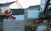 Ein Bauarbeiter klettert während Arbeiten aus dem Unterflurbehälter am Neuchlensteig 3. (Bild: Claudia Eugster)