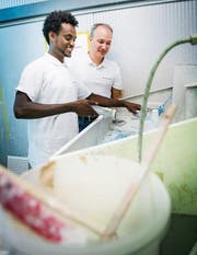 Lehrling Haile Major putzt Malerwerkzeug. Chef Roman Schefer schaut zu. (Bild: Andrea Stalder)