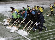 Aufwärmen der anderen Art: Ersatzspieler und Junioren des FC Wil schaufeln den Kunstrasen für das Testspiel frei. (Bild: Simon Dudle)