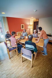 Eine gemütliche Runde: Tageszentrum-Leiterin Anna Viglione (orangefarbenes Oberteil) und ihre Kollegin (rot-weiss gestreiftes Oberteil) im Gespräch mit Tageszentrum-Gästen. (Bild: Reto Martin)