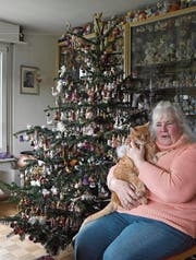 Elvira Bissegger sitzt mit einer ihrer drei Katzen vor dem Christbaum. (Bild: Yvonne Aldrovandi-Schläpfer)