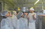 Aus hygienischen Gründen tragen die Schülerinnen Schutzkleidung, während sie den Weg der Milch zu Käse verfolgen. (Bild: Ramona Riedener)