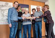 Sie teilen sich Brot vor den Plakaten der Fastenzeit: Alex Hutter, Rose-Marie Macher, Peter Baumann, Vreni Dietemann, Verena Fankhauser, Christof Kaiser, René Oettli und Edith Heiniger. (Bild: Samuel Koch)