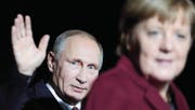 Russlands Präsident Wladimir Putin winkt in Berlin hinter Kanzlerin Angela Merkel den Kameras zu. (Bild: Markus Schreiber/AP)