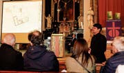 Kirchbürgerinnen und Kirchbürger lauschen den Ausführungen von Architekt Ronny Ambauen zur Planung des Mehrfamilienhauses Navan. Derweil scheint Kirchenverwaltungsratspräsident Stefan Meier im Hintergrund für ein gutes Gelingen des Projekts zu beten. (Bild: Rudolf Hirtl)
