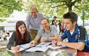Lernen unter besonderer Beobachtung im Schatten der Bäume: Die Schüler Nina Steffen und Felix Ritzi besprechen sich mit Immersionsklassen-Assistent Colin Browne und Prorektor Ruedi Herzog (stehend). (Bild: Donato Caspari)