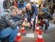 Der Schrein mit der Fliege Erika wird in den Boden der HSG eingelassen: Stifter Hans-Dietrich Reckhaus (im Anzug) und die Künstlerzwillinge Patrik und Frank Riklin (mit Mützen) sind an vorderster Front dabei. (Bild: Hanspeter Schiess)
