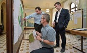 Bauamtschef Martin Belz (kniend) erklärt zwei Immobilienverwaltern im Foyer des Rathauses die Änderungen am Zonenplan. (Bild: Mario Testa)