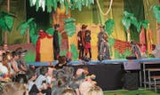 Mowgli das Dschungelkind, angenommen von den Wölfen, behütet von Bär Baloo und Panther Bagheera (links der Schülerchor).
