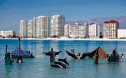 Geht die Welt baden? Während der Klimakonferenz setzte Greenpeace die Denkmäler dieser Welt ins Meerwasser vor Cancún. (Bild: ap/Eduardo Verdugo)