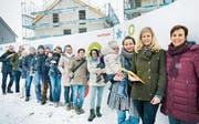 Sie wünschen sich einen Kinderhort: Eine Gruppe Eltern posiert mit den Petitionärinnen vor der Raiffeisen-Baustelle, wo ein Generationenraum entsteht. Dieser wäre ein möglicher Standort. (Bild: Andrea Stalder)
