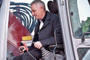 Spatenstich: Bauherr Ruedi Menet hebt die erste Schaufel mit dem Bagger aus. (Bild: IKS)
