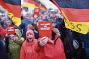 Demonstranten protestieren in Finsterwalde (Brandenburg) während einer Wahlkampfveranstaltung der CDU gegen Bundeskanzlerin Angela Merkel. (Bild: Ralf Hirschberger/DPA ()