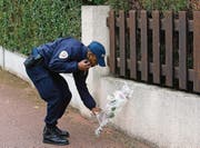 Im Gedenken an den ermordeten Berufskollegen: Ein Polizist legt am Tatort eine Blume nieder. (Bild: ap/Thibault Camus)