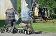 Zentrumsbewohner verfolgen gespannt, wie Baukommissionspräsident Ruedi Zbinden mit dem Bagger das erste Loch gräbt. (Bild: Mario Testa)