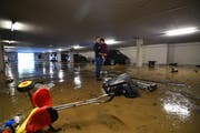 Anita Karaqi hält Ihre Tochter auf dem Arm und schaut sich den Schaden an. Hinter den beiden steht das Auto der Familie. Das Kindervelo und den Kindersitz der Tochter hat das Wasser vom Abstellplatz quer durch die stark verschmutzte Tiefgarage geschwemmt. (Bild: Manuel Nagel)
